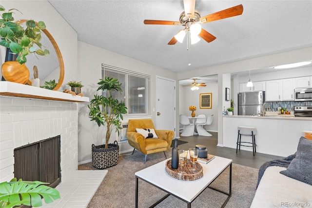 living area with a brick fireplace, ceiling fan, baseboards, and a textured ceiling