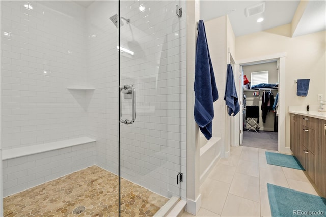 bathroom featuring visible vents, vanity, a walk in closet, tile patterned floors, and a stall shower
