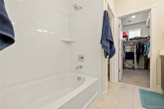 bathroom featuring tile patterned flooring, baseboards, a walk in closet, and bathing tub / shower combination