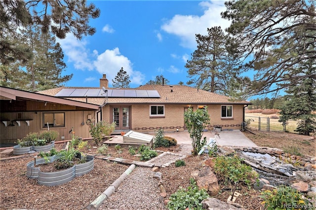 back of property with solar panels and a patio area