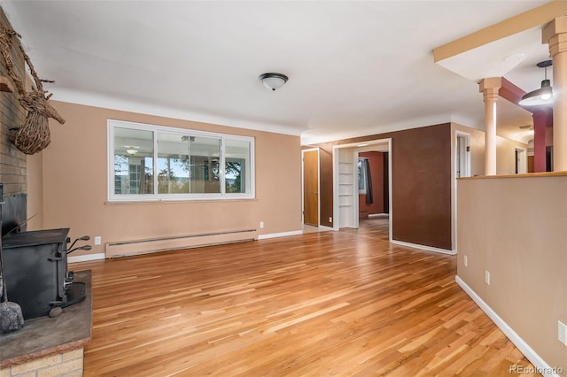 living room featuring baseboard heating, light hardwood / wood-style flooring, ornate columns, and a fireplace