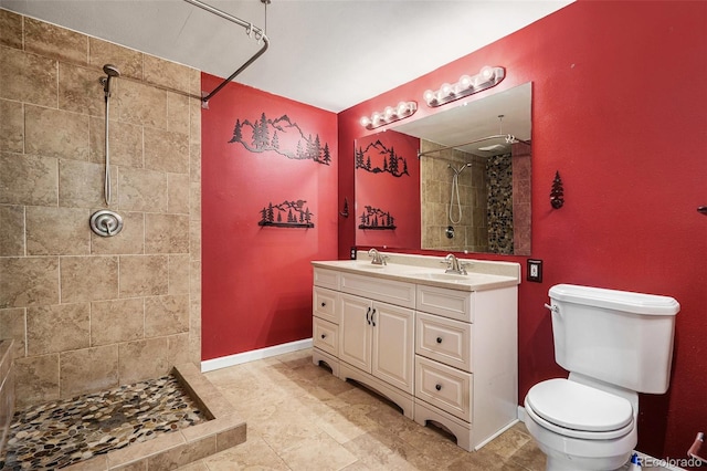 bathroom with vanity, toilet, and a tile shower