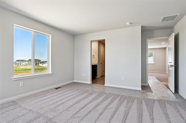 unfurnished bedroom with ensuite bath and carpet floors