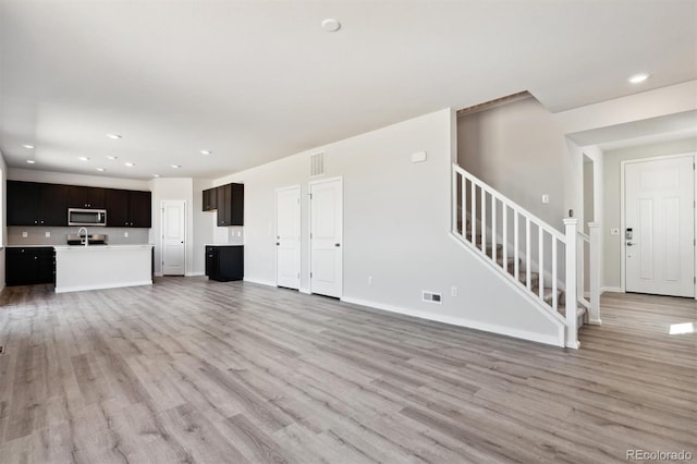 unfurnished living room featuring light hardwood / wood-style flooring and sink