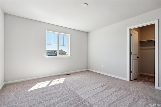 unfurnished bedroom with light colored carpet, a spacious closet, and a closet