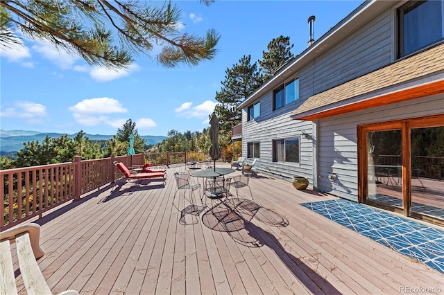 wooden terrace featuring a mountain view and outdoor dining area