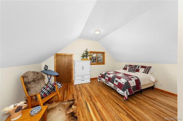 bedroom featuring light wood-style flooring, baseboards, and vaulted ceiling