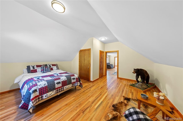 bedroom with light wood-type flooring, lofted ceiling, and baseboards