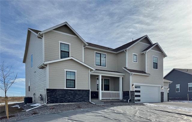 view of front of property with central AC unit, covered porch, a garage, stone siding, and driveway