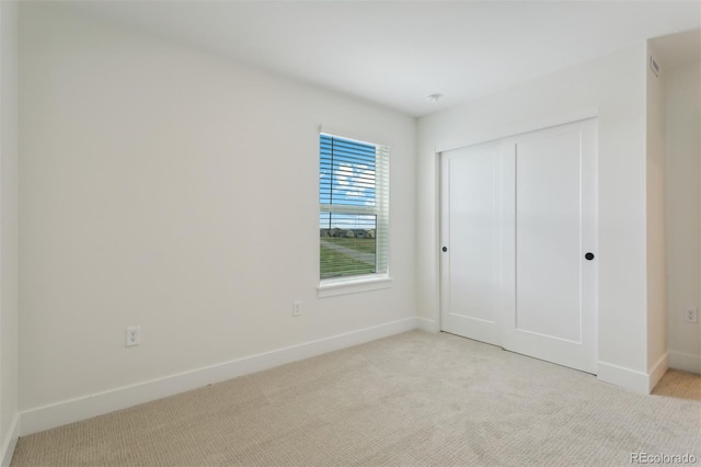 unfurnished bedroom with light carpet and a closet