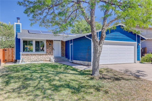 ranch-style home with a garage, a front lawn, and solar panels