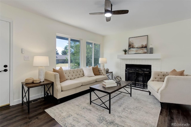 living room featuring a brick fireplace, dark hardwood / wood-style floors, and ceiling fan