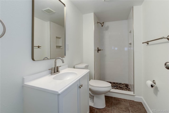 bathroom with tile patterned flooring, vanity, tiled shower, and toilet