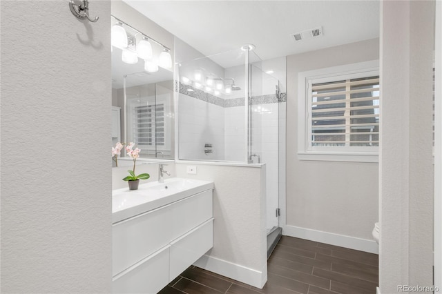 9861 E Ohio Ave, Denver, CO 80247 - full bath featuring vanity, a shower stall, wood finish floors, baseboards, and a textured wall