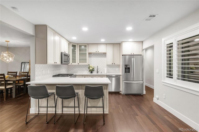 9861 E Ohio Ave, Denver, CO 80247 - kitchen featuring appliances with stainless steel finishes, a peninsula, tasteful backsplash, dark wood-style floors, and recessed lighting