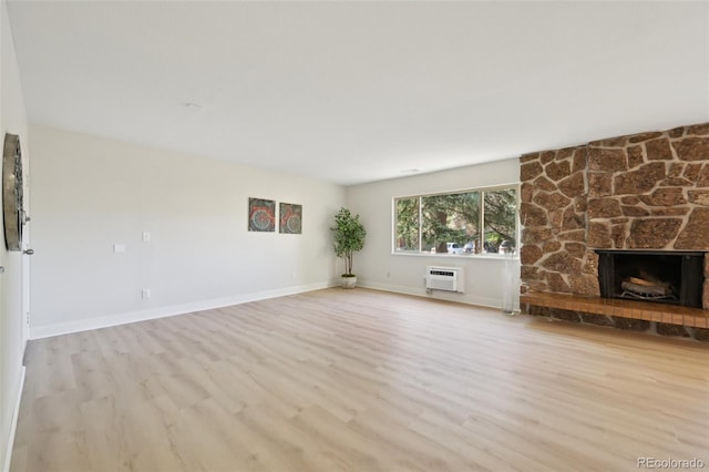 3365 Chisholm Trl Unit B102, Boulder, CO 80301 - unfurnished living room with an AC wall unit, wood finished floors, a stone fireplace, and baseboards