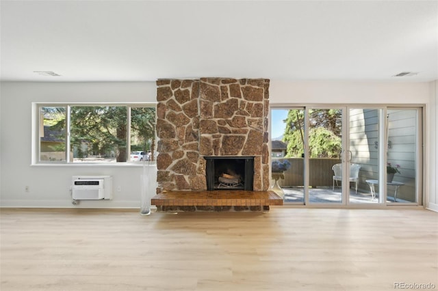 3365 Chisholm Trl Unit B102, Boulder, CO 80301 - unfurnished living room with wood finished floors, an AC wall unit, a stone fireplace, and baseboards