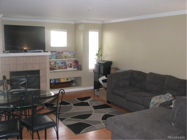 living room with a tiled fireplace, wood-type flooring, and ornamental molding