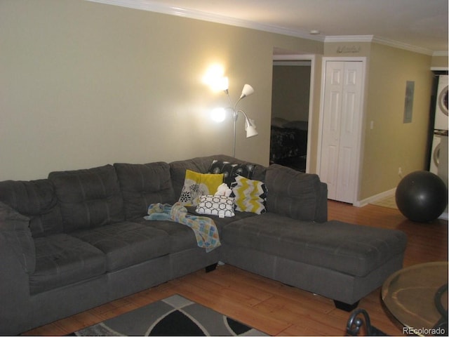 living room with hardwood / wood-style flooring, stacked washer / dryer, and ornamental molding