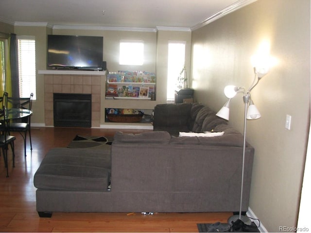 living room featuring a tiled fireplace, hardwood / wood-style floors, and ornamental molding