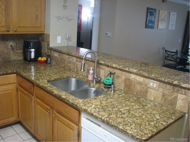 kitchen with decorative backsplash, kitchen peninsula, light stone countertops, and sink