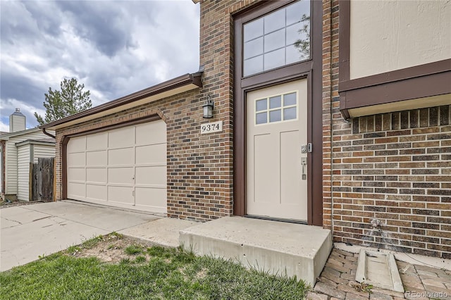 property entrance with brick siding, concrete driveway, and a garage