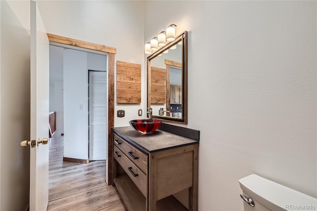 bathroom featuring wood finished floors, toilet, and vanity