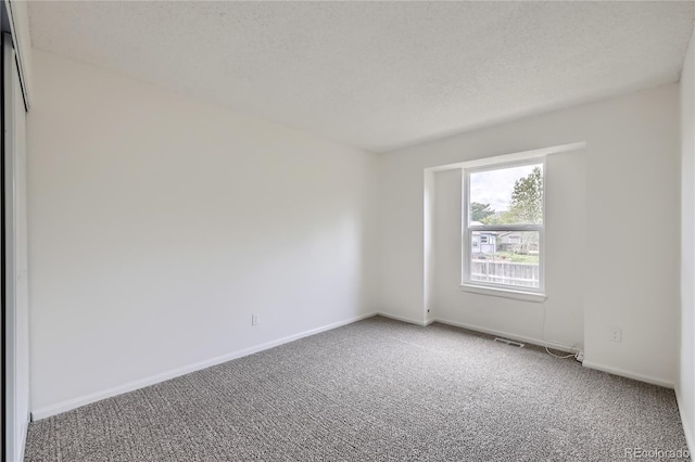 carpeted spare room featuring baseboards and a textured ceiling