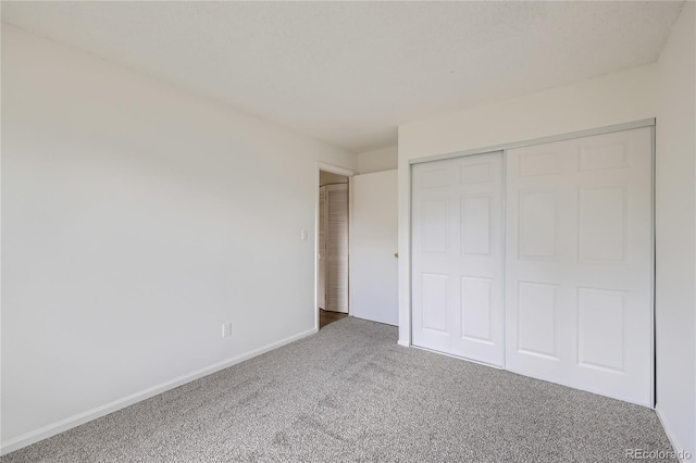 unfurnished bedroom featuring carpet, baseboards, and a closet