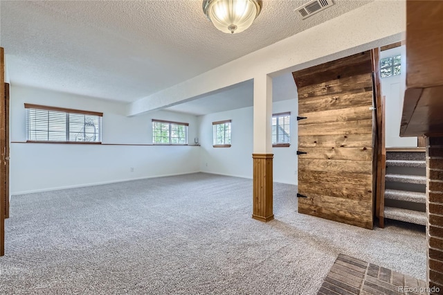 below grade area with carpet, stairs, a textured ceiling, and baseboards