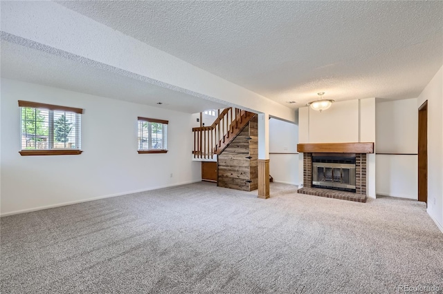 unfurnished living room featuring a textured ceiling, carpet floors, stairway, a brick fireplace, and baseboards