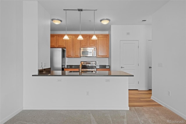 4100 Albion St Unit 320, Denver, CO 80216 - kitchen featuring appliances with stainless steel finishes, dark countertops, light carpet, and pendant lighting