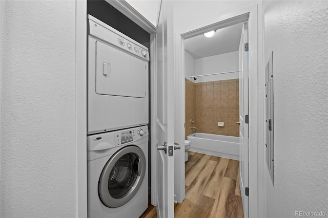 4100 Albion St Unit 320, Denver, CO 80216 - washroom with estacked washer and dryer, wood finished floors, and a textured wall