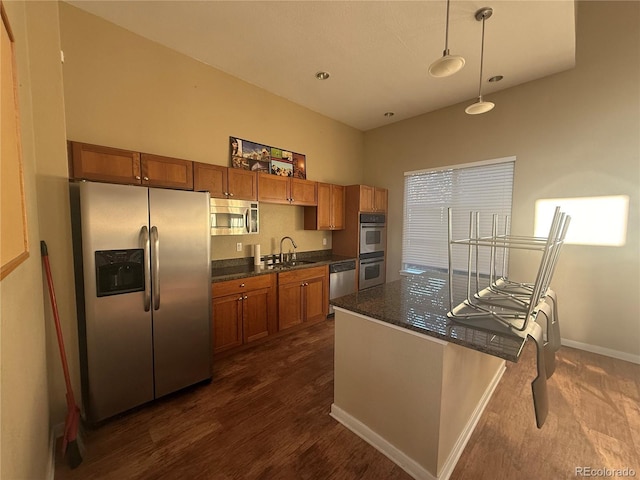 4100 Albion St Unit 320, Denver, CO 80216 - kitchen with stainless steel appliances, brown cabinetry, hanging light fixtures, and dark wood finished floors