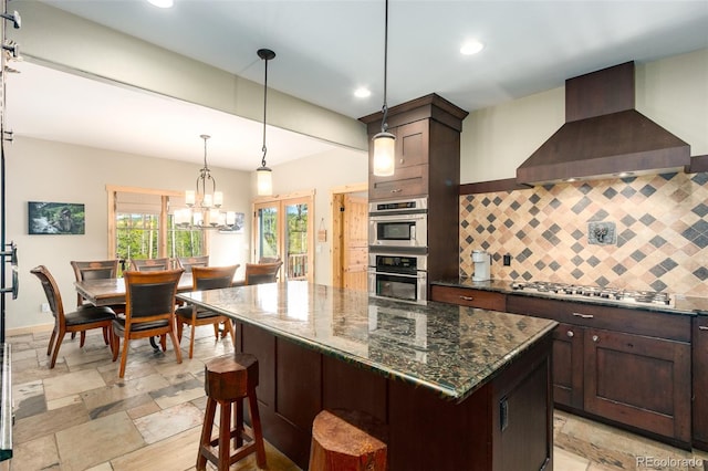 632 Gcr 662, Grand Lake, CO 80447 - kitchen with wall chimney range hood, dark brown cabinetry, stainless steel gas stovetop, backsplash, and a kitchen island