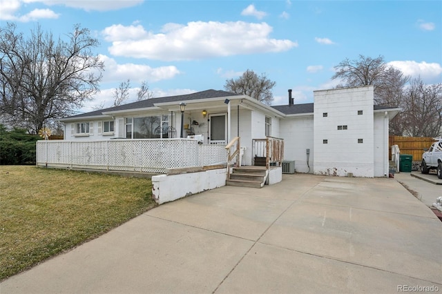 view of front facade with central AC, a front yard, and fence