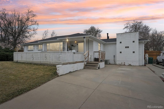 view of front of home with a porch, central air condition unit, fence, and a lawn