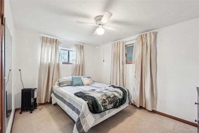 bedroom with radiator heating unit, light colored carpet, baseboards, and ceiling fan