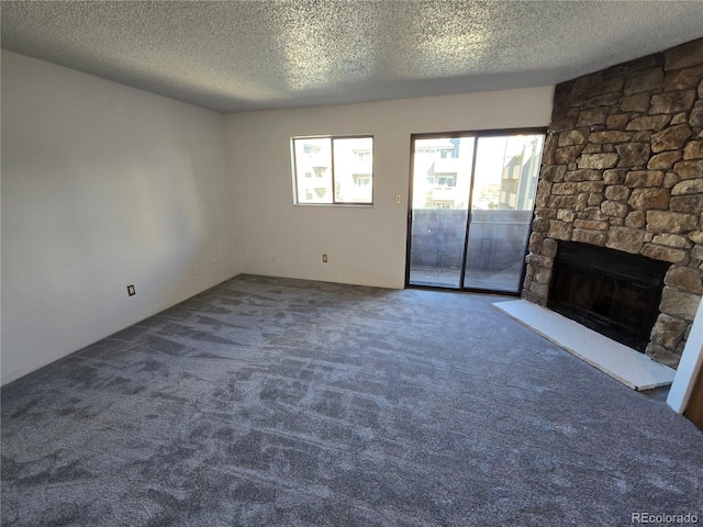 unfurnished living room with carpet floors, a textured ceiling, and a stone fireplace