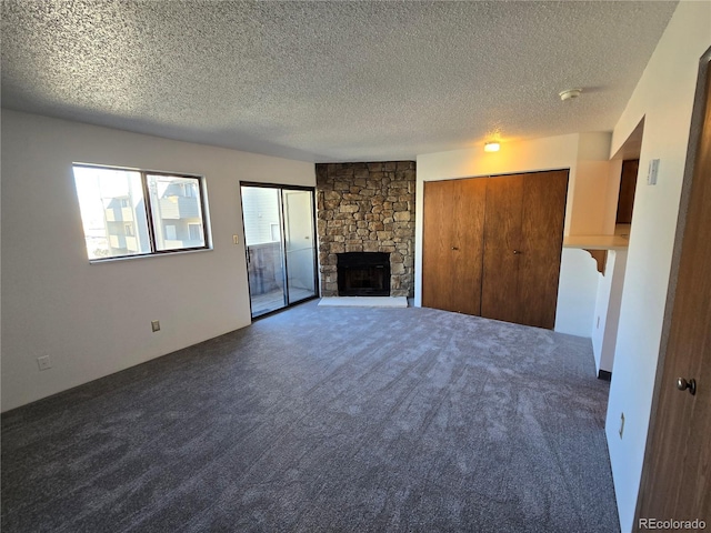 unfurnished living room featuring carpet, a textured ceiling, and a stone fireplace