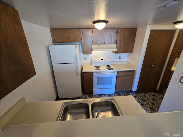 kitchen with white appliances, visible vents, light countertops, under cabinet range hood, and a sink