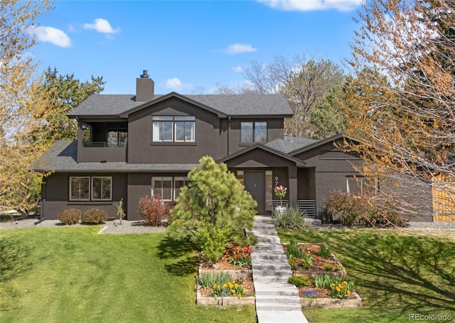 craftsman-style house with a balcony, a chimney, a shingled roof, a front yard, and stucco siding