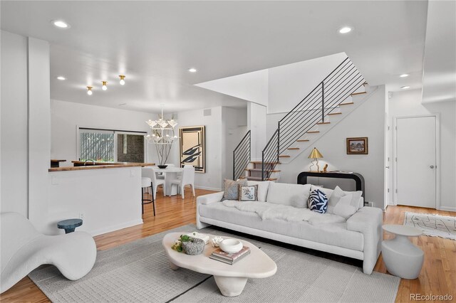 living room featuring stairs, wood finished floors, a chandelier, and recessed lighting