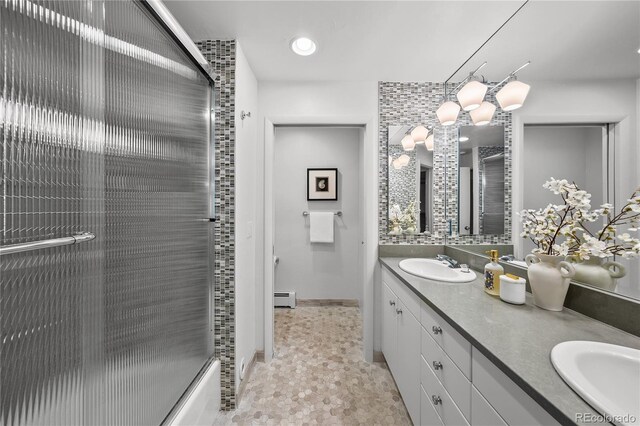full bath with baseboard heating, a sink, and double vanity
