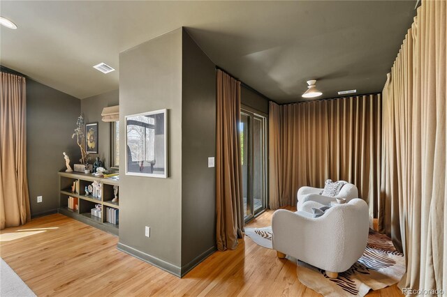 sitting room with baseboards, visible vents, and light wood-style floors