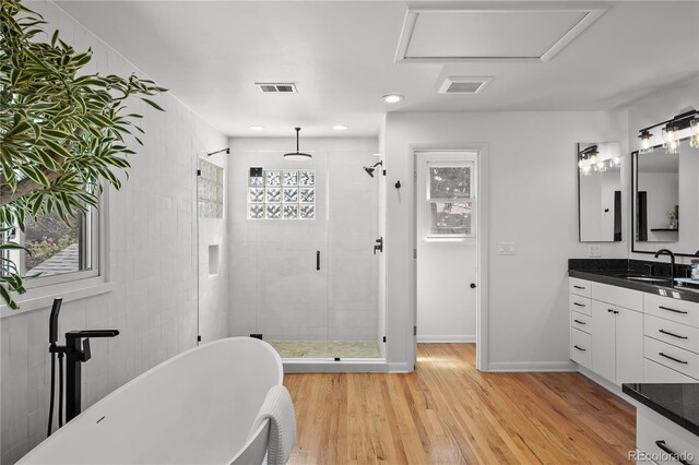 bathroom with a shower stall, wood finished floors, visible vents, vanity, and a soaking tub