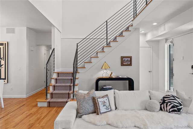 living area featuring baseboards, wood finished floors, and stairs