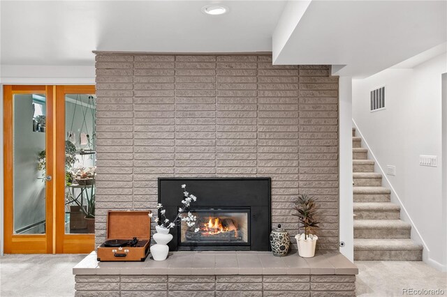 details with carpet flooring, baseboards, a brick fireplace, and visible vents
