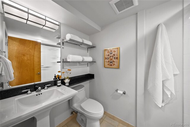bathroom featuring tile patterned flooring, visible vents, toilet, baseboards, and walk in shower