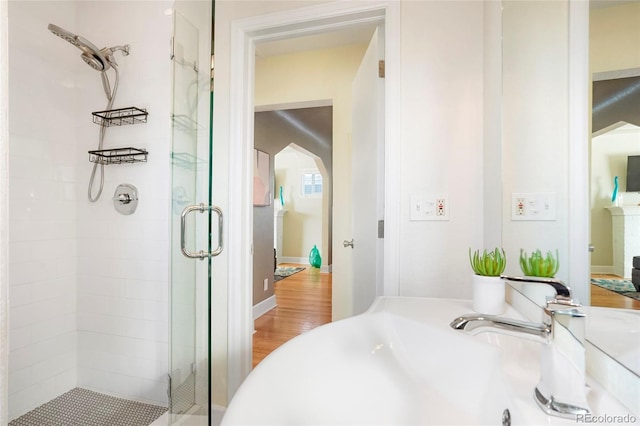 bathroom with hardwood / wood-style flooring, a shower with shower door, and sink